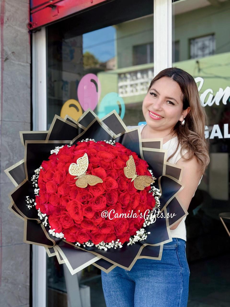 Camila sosteniendo un ramo de rosas rojas frente a su tienda